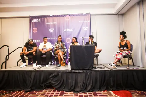Five panelists sit on a raised stage in front of a purple WakandaCon backdrop.
