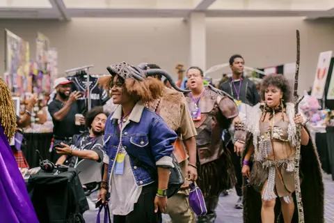 A parade of cosplayers in masks and leather moves through the Marketplace aisle.