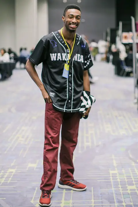 A young man in a baseball jersey stands in the concourse.