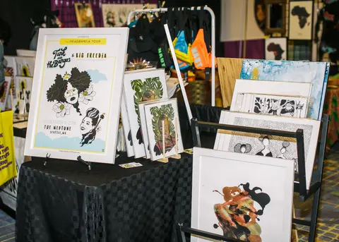 Black and white prints of illustrated faces stand in bins on a vendor table.