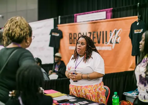 A vendor talks with visitors under an orange Bronzeville banner.
