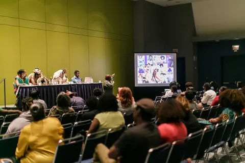 Attendees watch a panel with a slide on the screen.